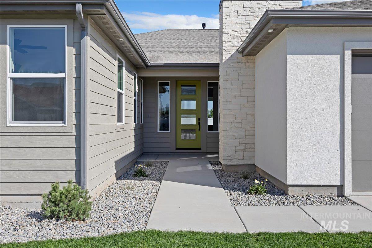 Doorway to property featuring stone siding and roof with shingles