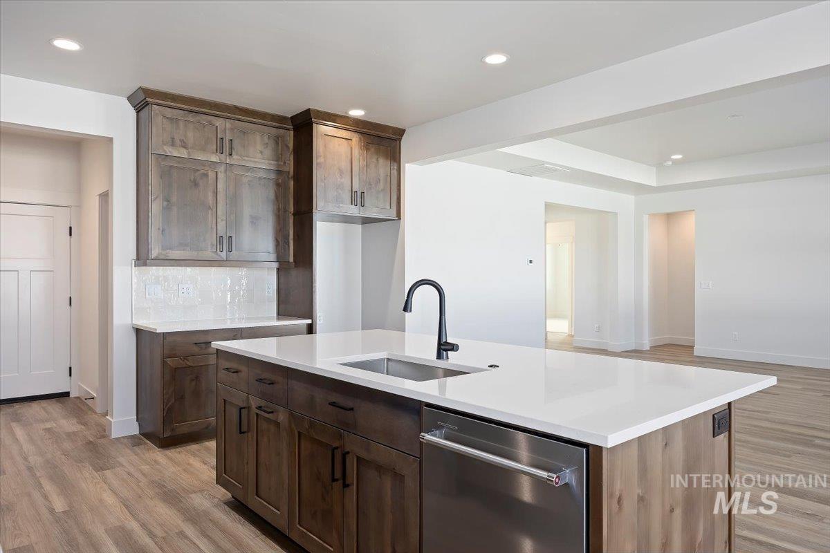 Kitchen with stainless steel dishwasher, light wood-style floors, an island with sink, recessed lighting, and open floor plan