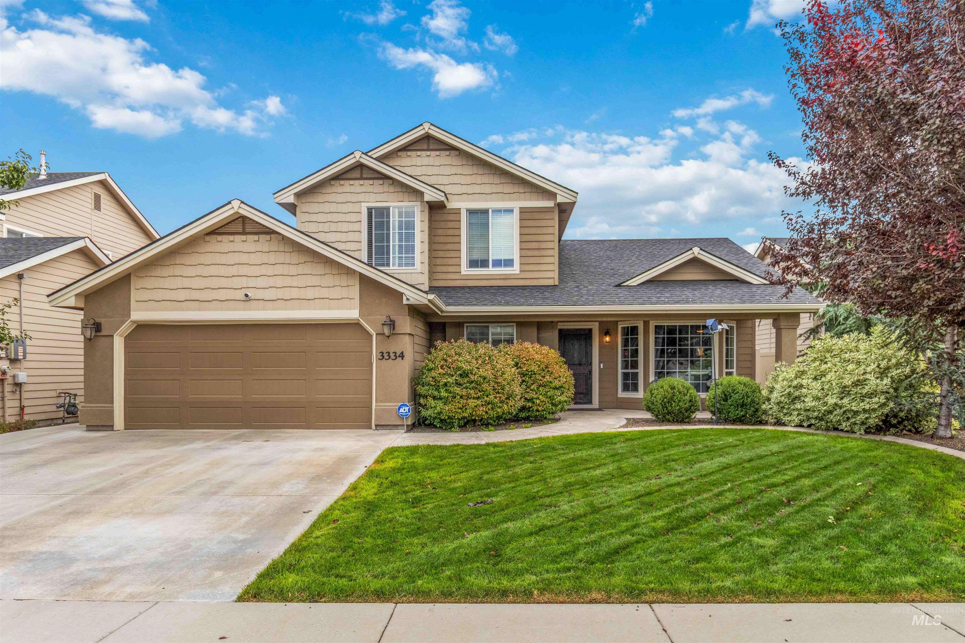 View of front of property featuring a front yard, concrete driveway, a shingled roof, and an attached garage