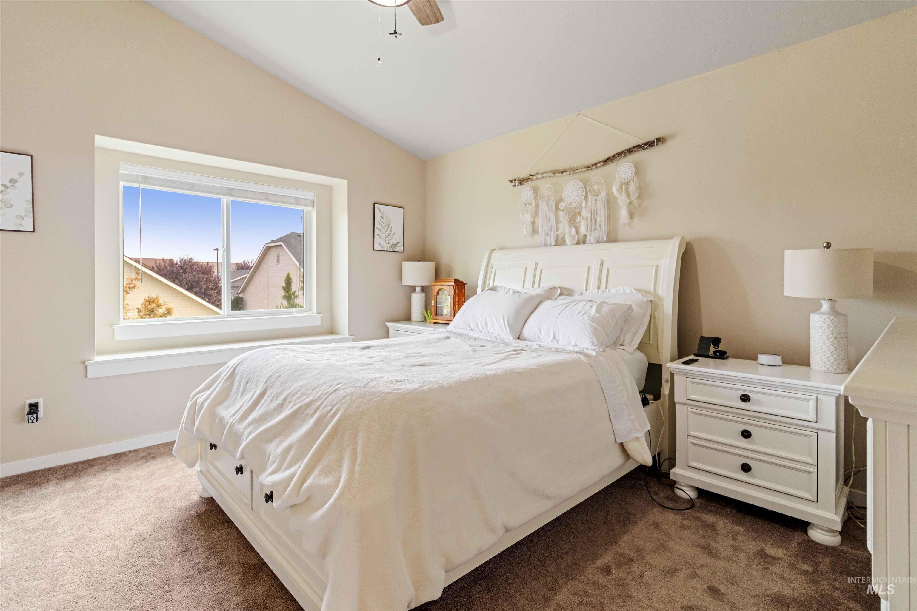 Bedroom with dark carpet, vaulted ceiling, and ceiling fan