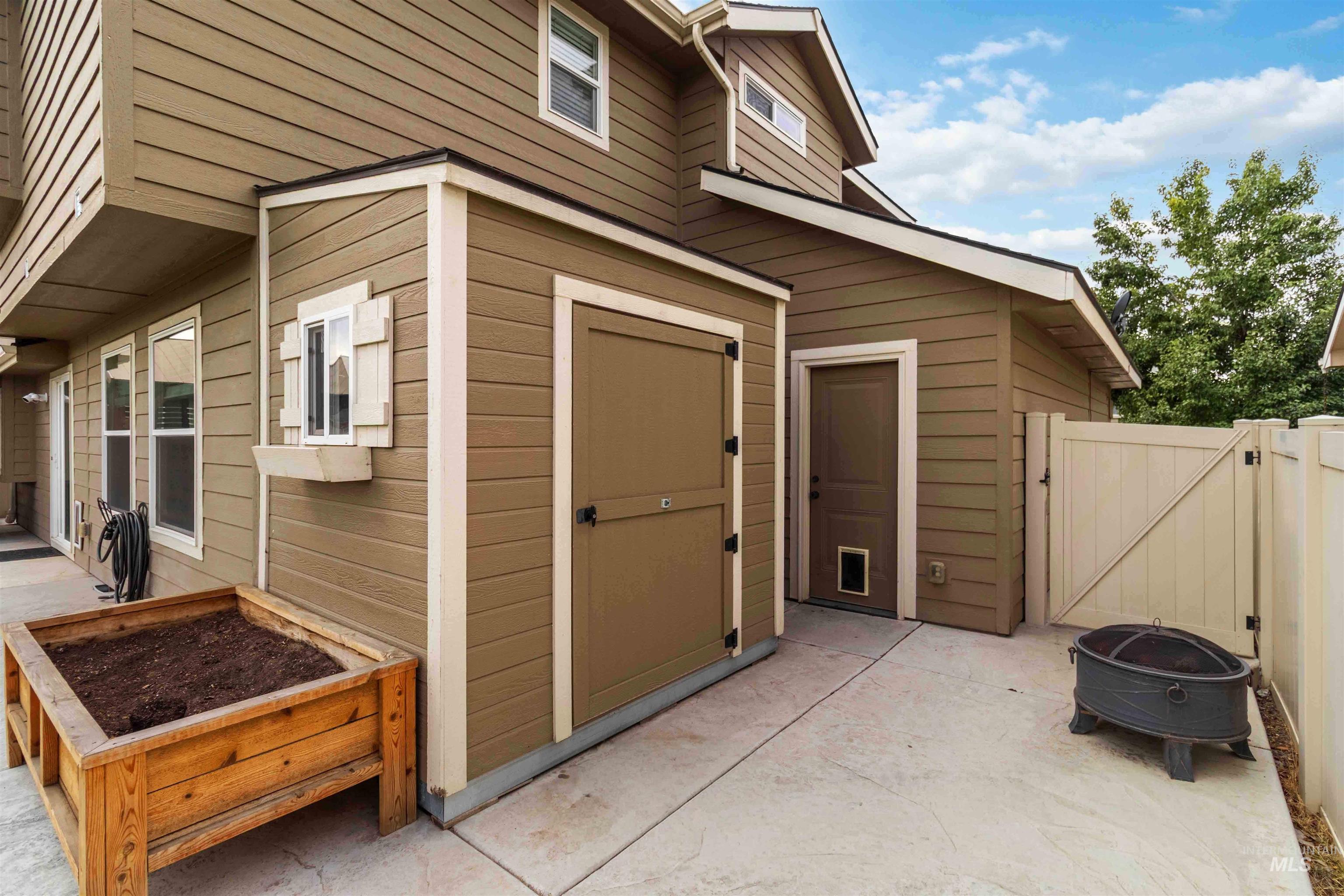 View of outbuilding with a gate, a fire pit, and a garden
