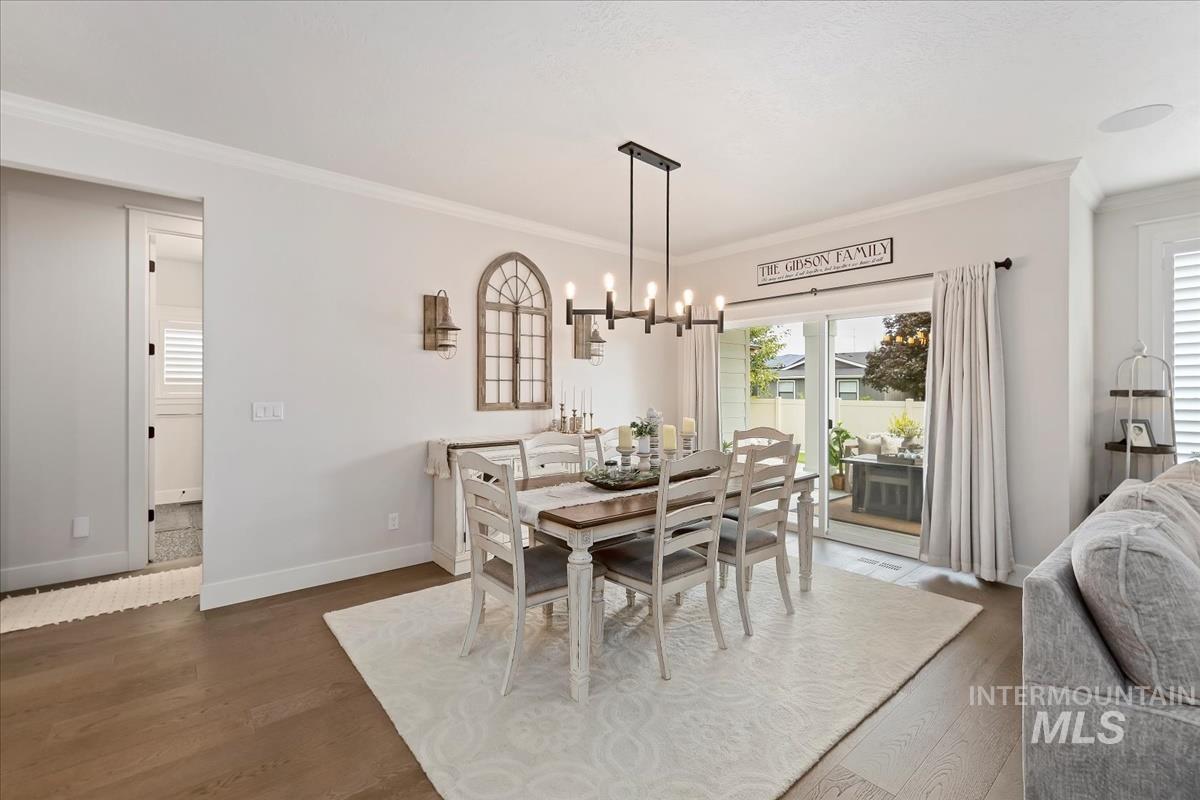 Dining room featuring ornamental molding, a chandelier, and dark wood-style floors