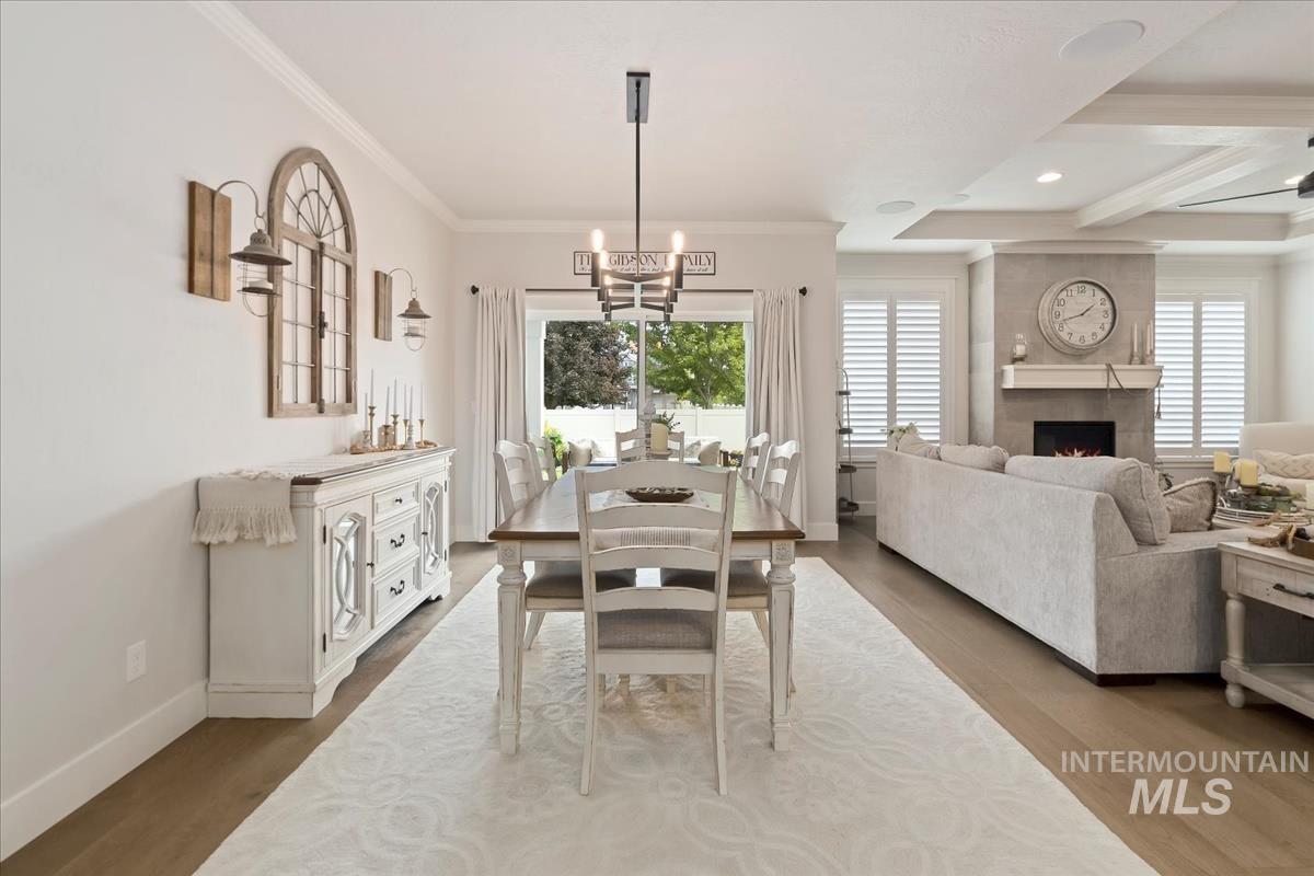 Dining area featuring a fireplace, wood finished floors, a chandelier, recessed lighting, and crown molding