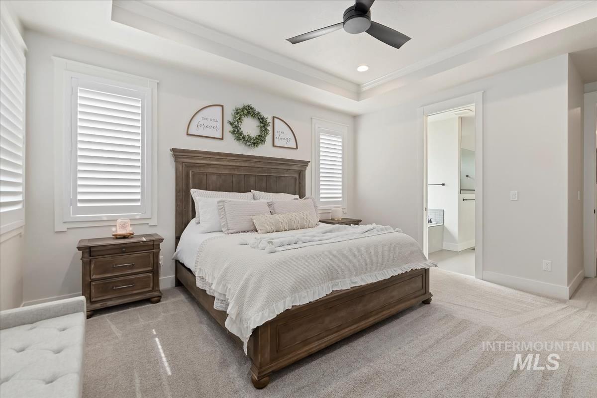 Bedroom with a tray ceiling, light colored carpet, a ceiling fan, and recessed lighting