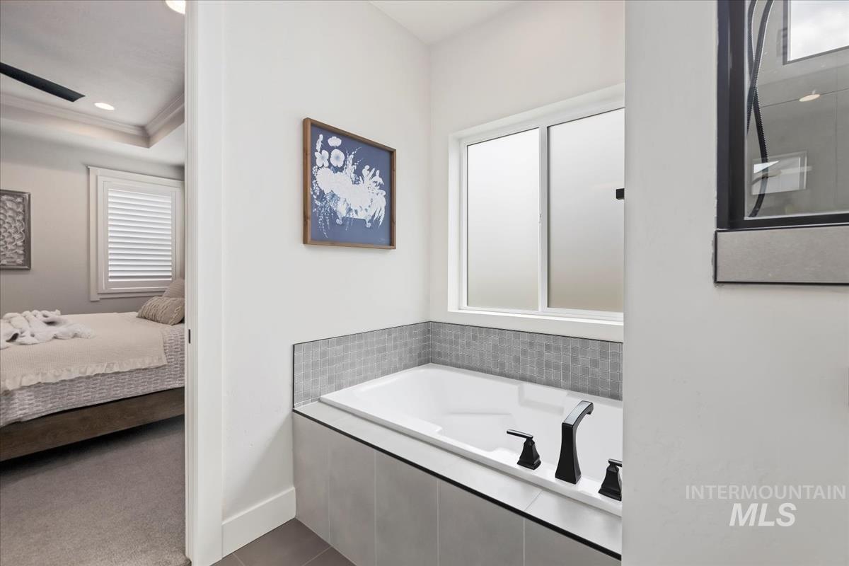 Ensuite bathroom with a garden tub, recessed lighting, dark tile patterned floors, and crown molding