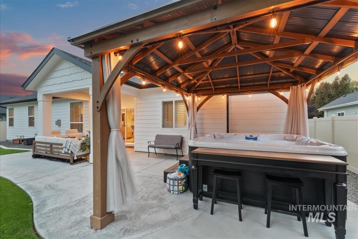 Patio terrace at dusk with an outdoor hangout area, a patio area, a hot tub, and a gazebo