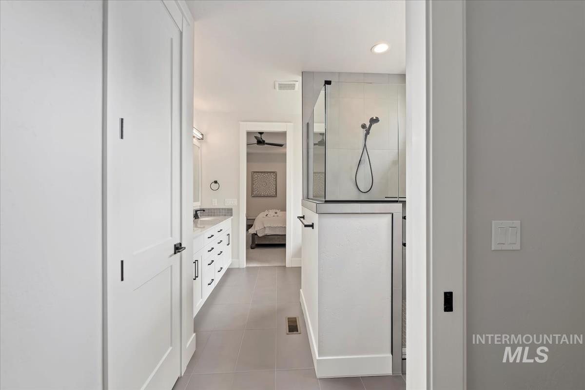 Ensuite bathroom with walk in shower, double vanity, light tile patterned flooring, ceiling fan, and recessed lighting