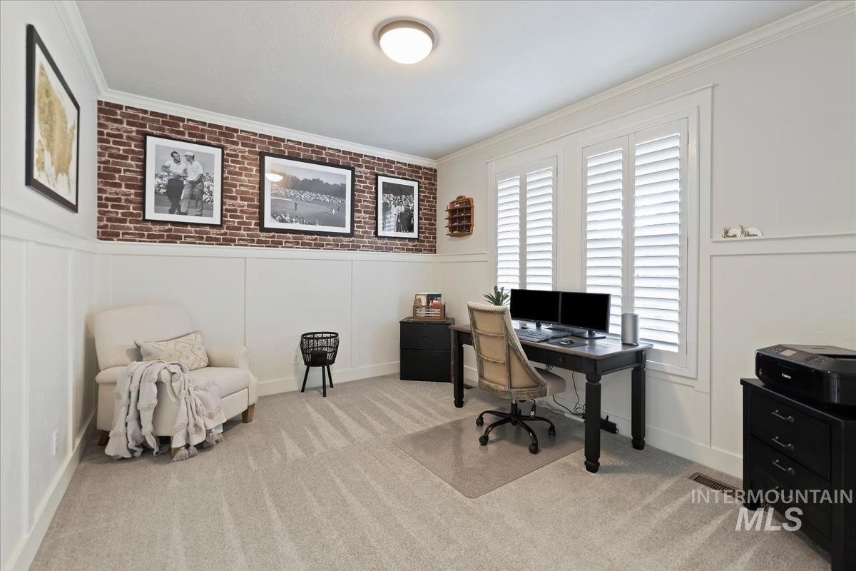 Office area featuring ornamental molding, light carpet, a wainscoted wall, and a decorative wall
