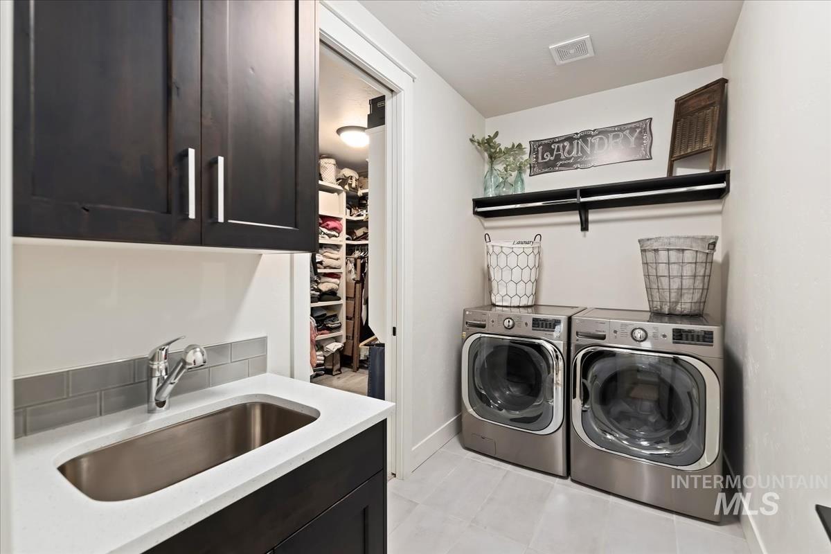 Washroom featuring light tile patterned floors, separate washer and dryer, and cabinet space