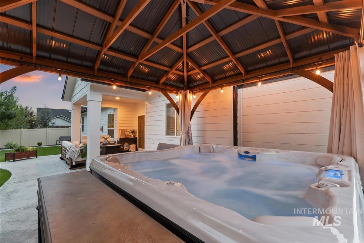 Patio terrace at dusk with a hot tub, a patio area, and a gazebo
