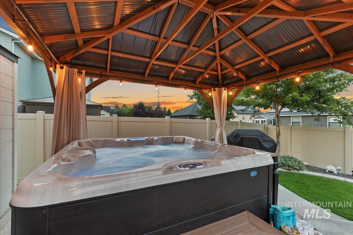 Fenced backyard featuring a gazebo, area for grilling, a hot tub, and a patio area