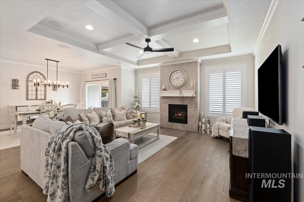 Living area featuring ornamental molding, a fireplace, coffered ceiling, beam ceiling, and wood finished floors