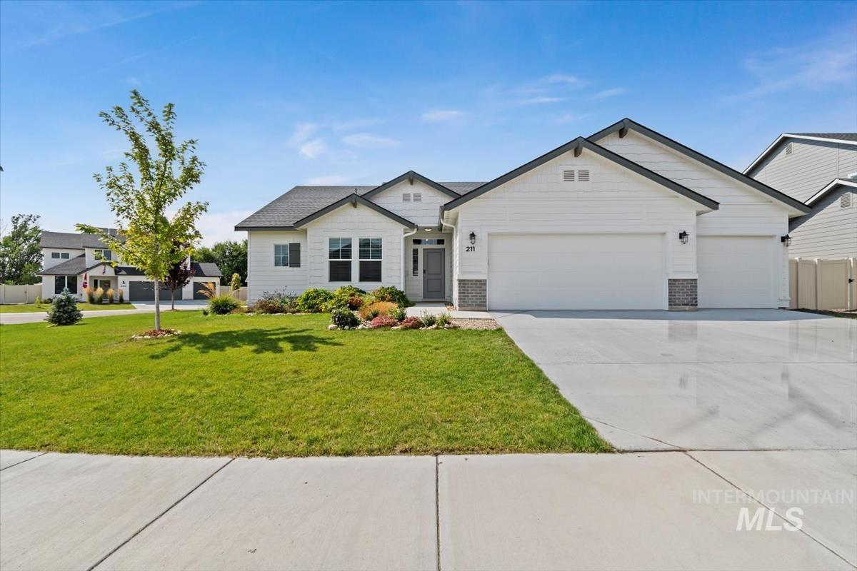 View of front of property with concrete driveway, an attached garage, and a front lawn