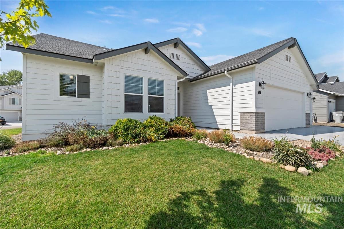 Ranch-style house with a garage, a front yard, a shingled roof, and driveway