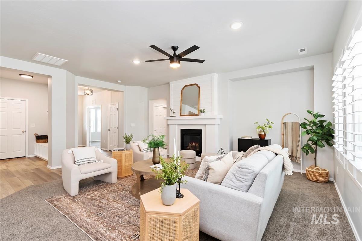 Living area with a fireplace, a ceiling fan, carpet floors, and recessed lighting