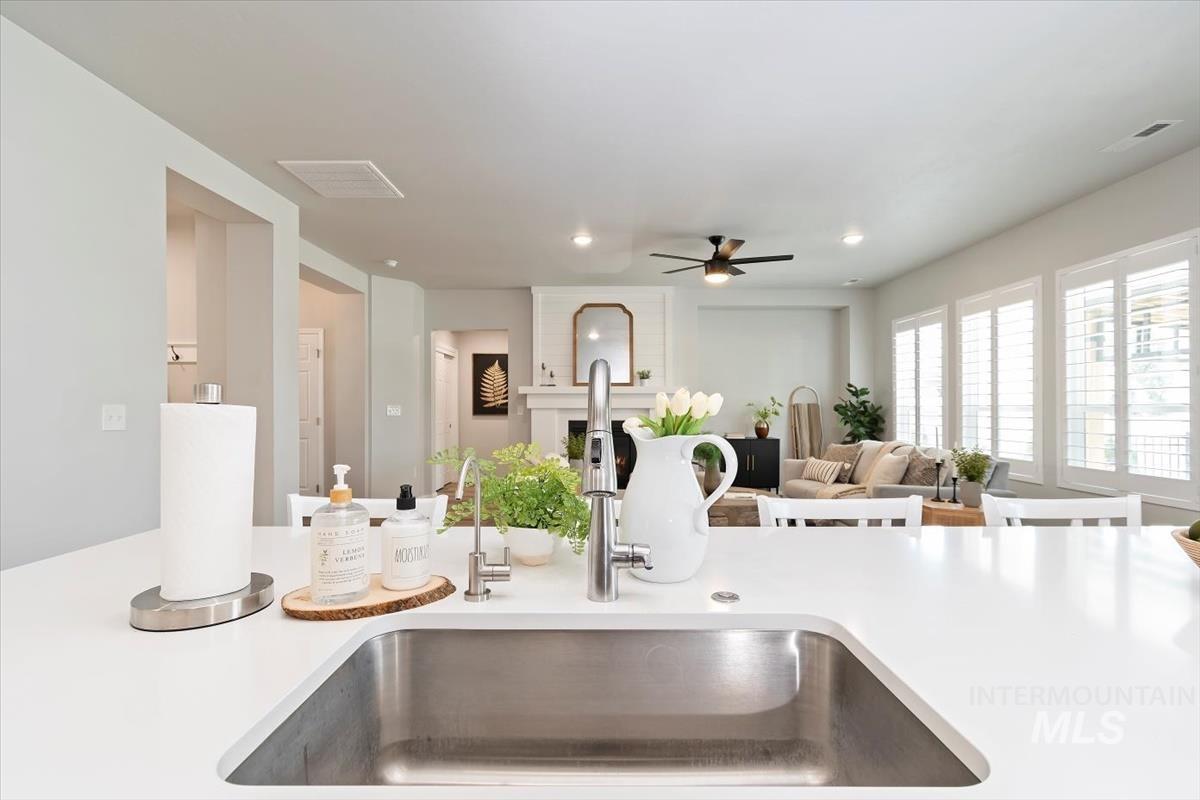 Kitchen view of recessed lighting, a ceiling fan, and light stone counters