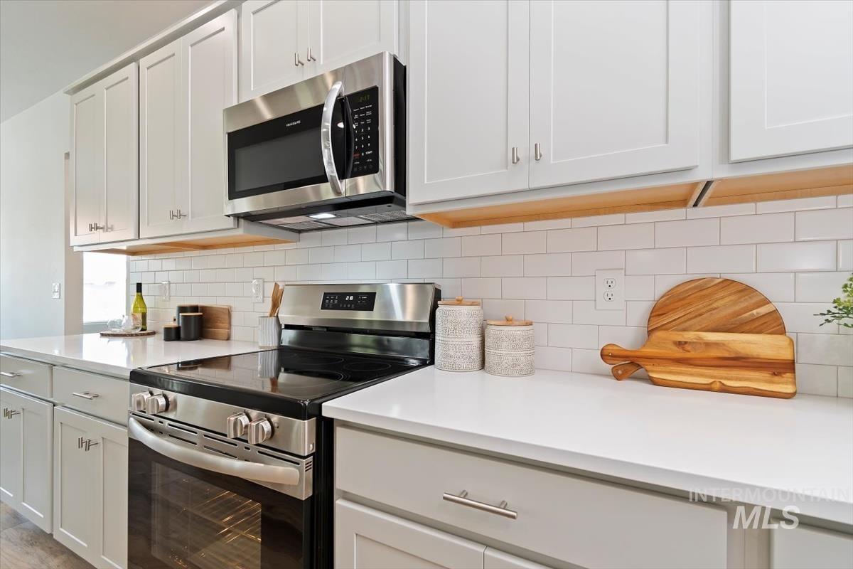 Kitchen with appliances with stainless steel finishes, white cabinets, and backsplash