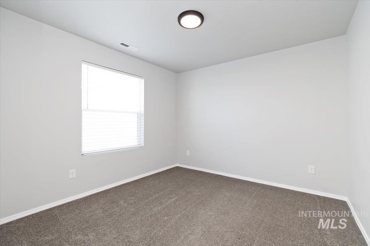 Spare room with dark colored carpet and baseboards