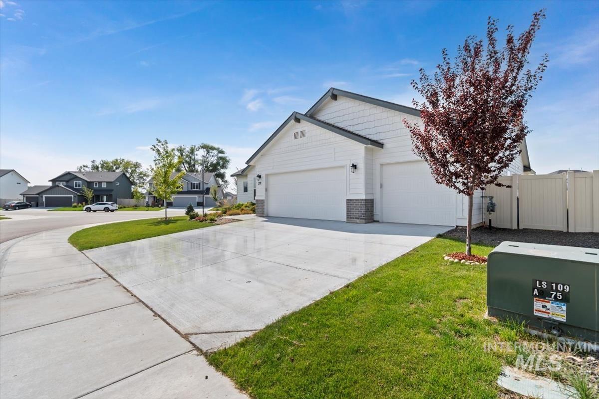 View of side of home featuring driveway, a lawn, an attached garage, a residential view, and a gate