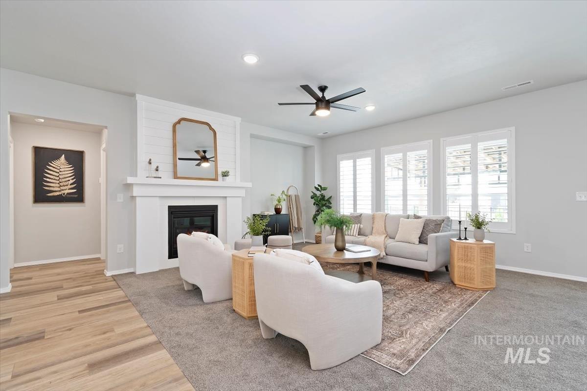 Living room featuring a large fireplace, recessed lighting, ceiling fan, and light wood-style flooring