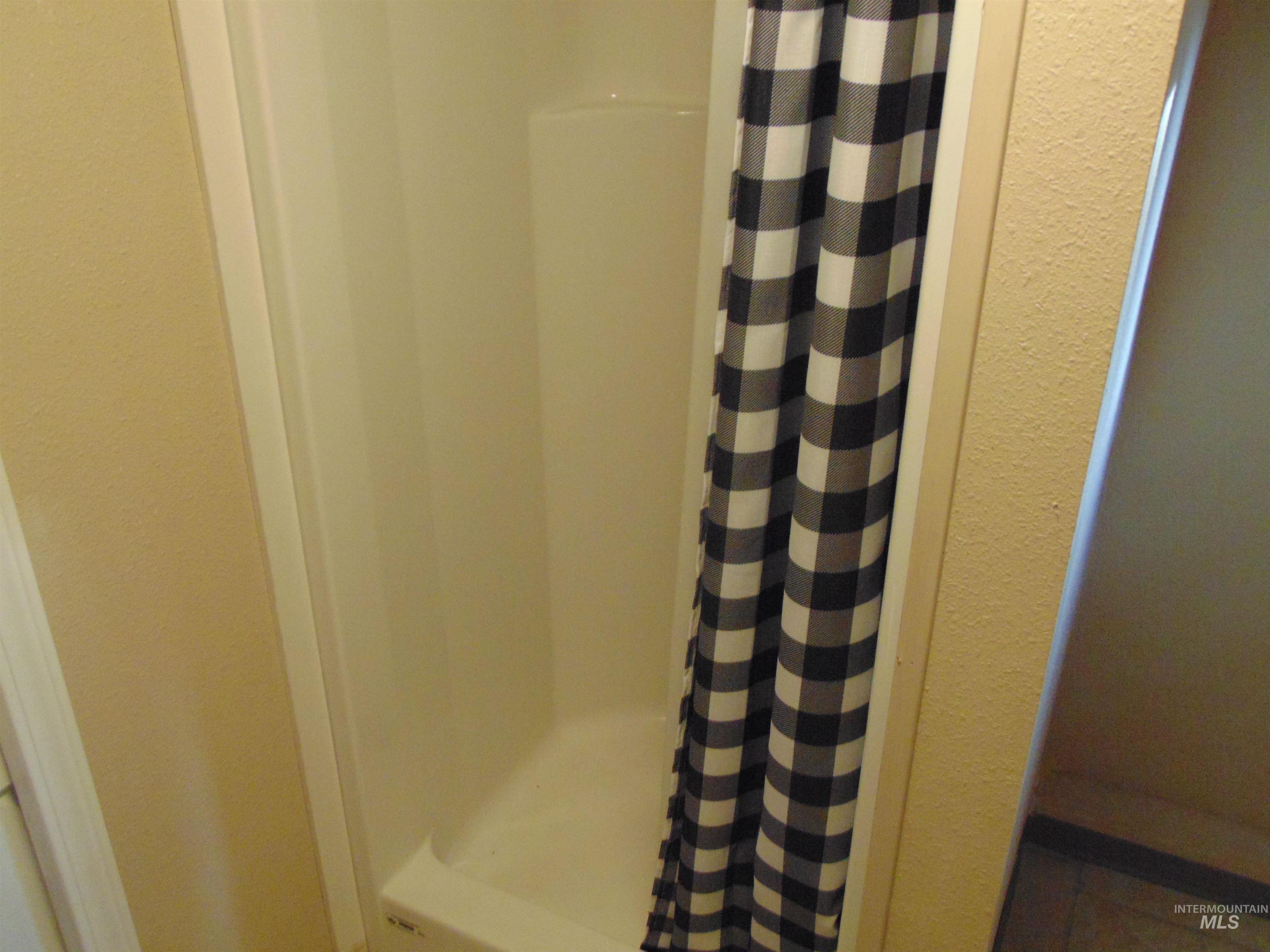 Bathroom featuring a shower with shower curtain and a textured wall