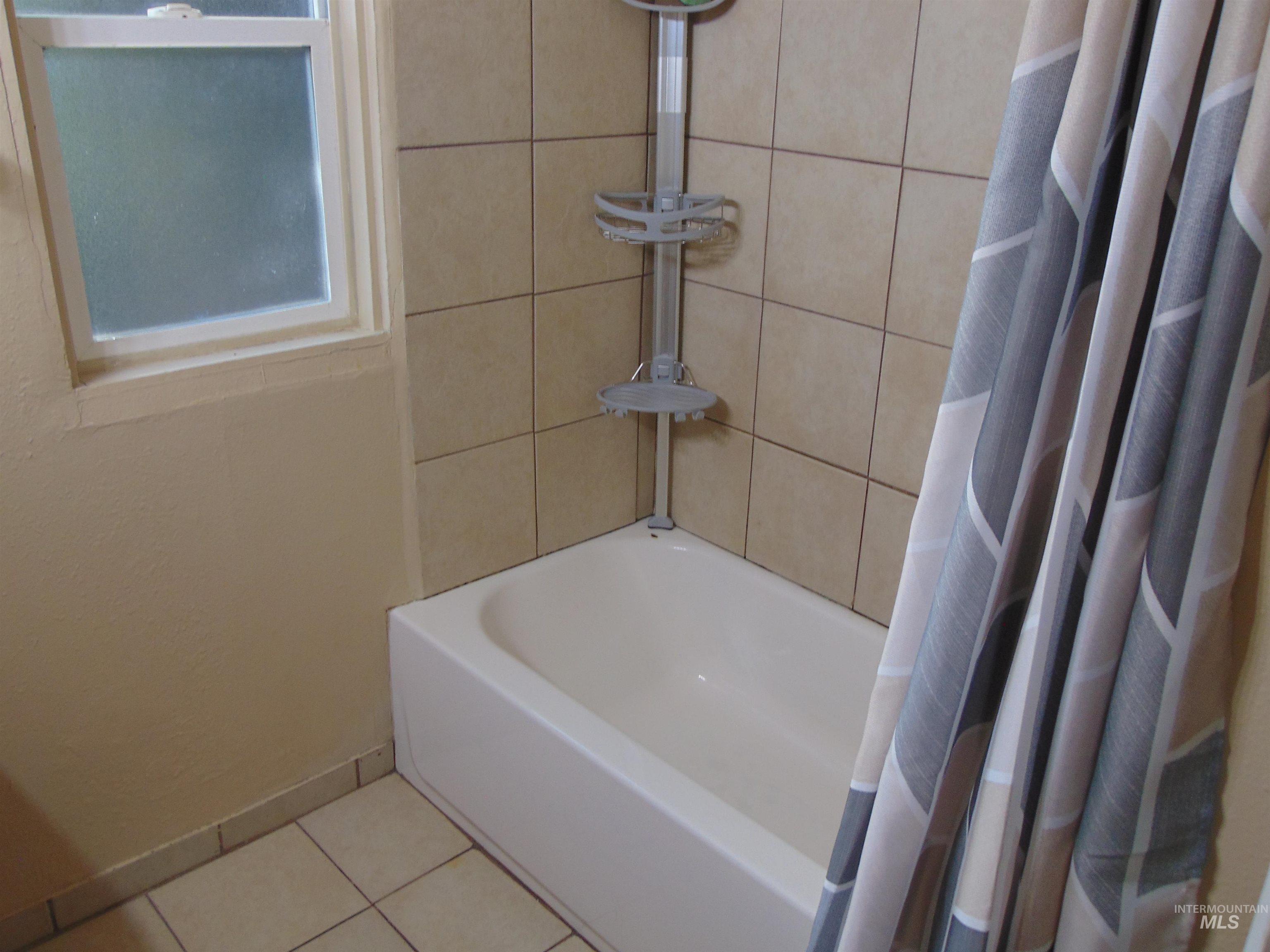 Bathroom featuring shower / tub combo with curtain and tile patterned floors