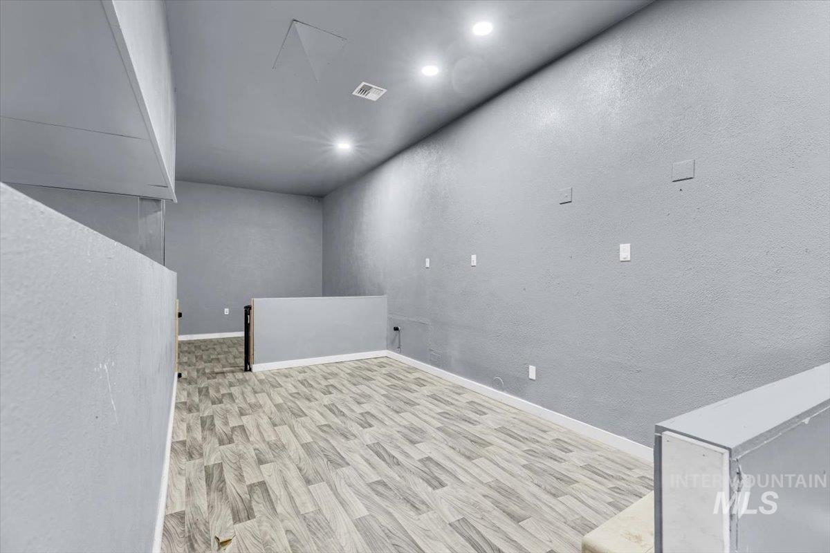 Empty room featuring a textured wall, light wood-type flooring, and recessed lighting