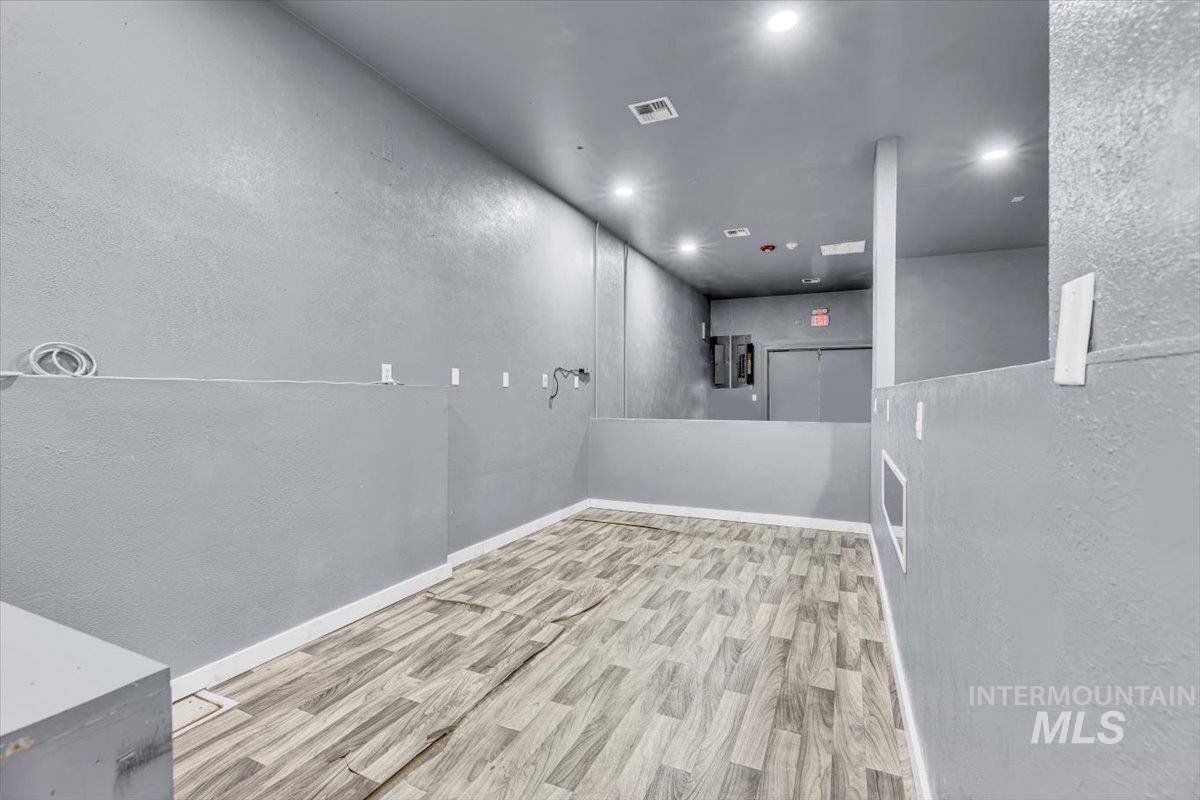 Unfurnished room with a textured wall, light wood-style floors, and recessed lighting