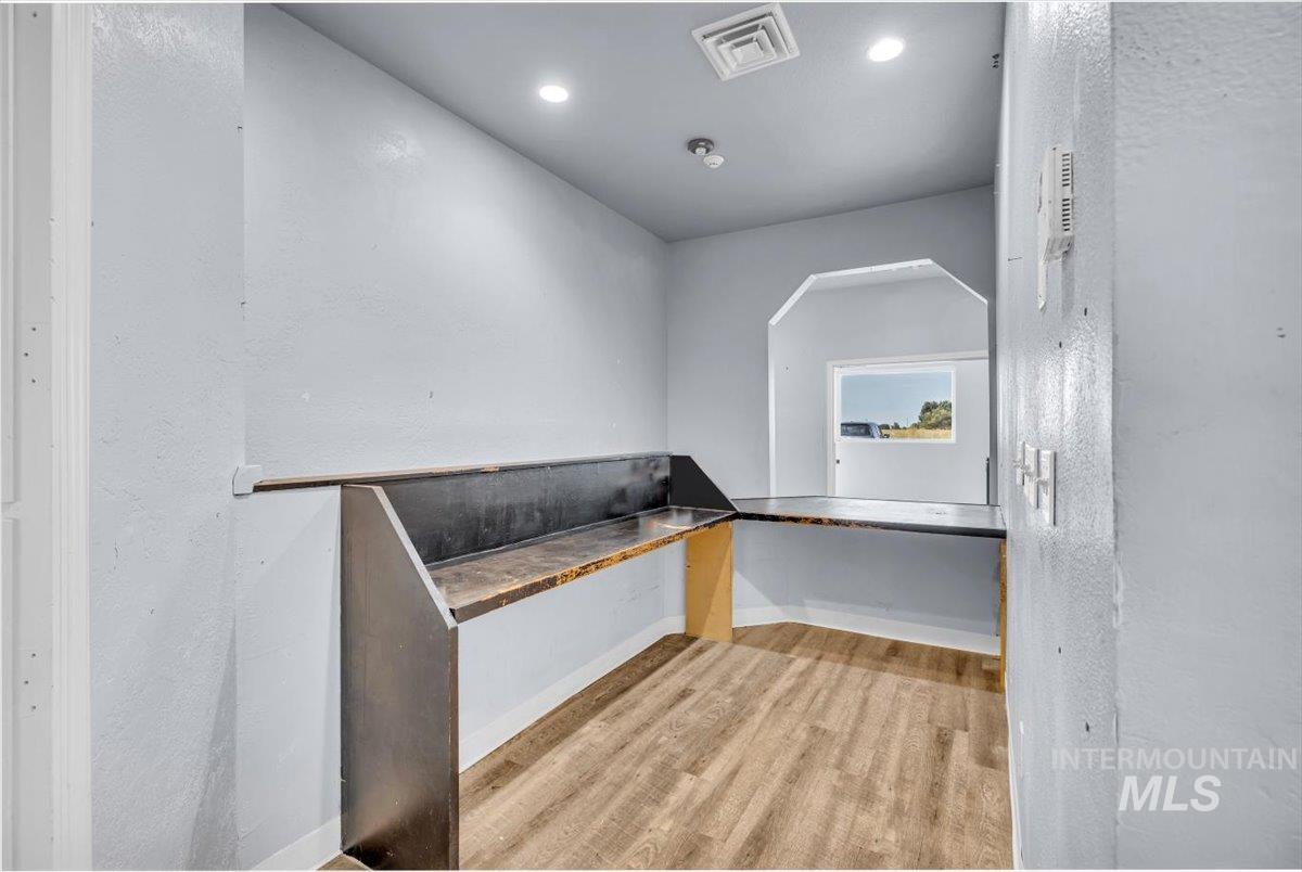Unfurnished office with light wood-type flooring, a textured wall, and recessed lighting