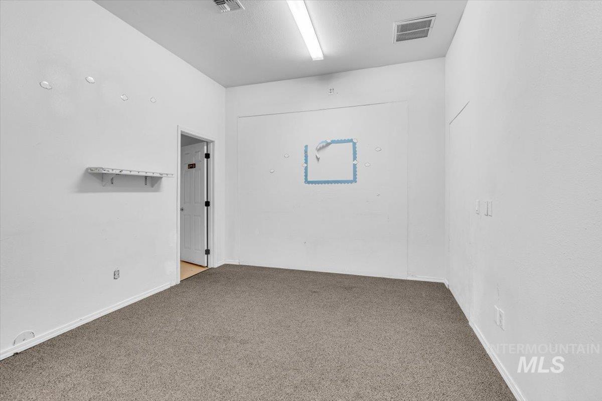Carpeted spare room featuring baseboards