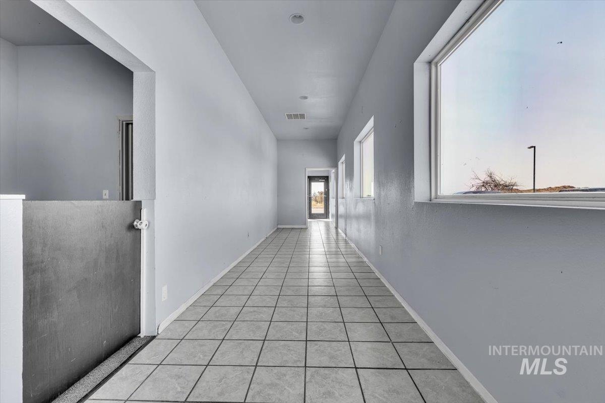 Corridor featuring light tile patterned flooring and baseboards