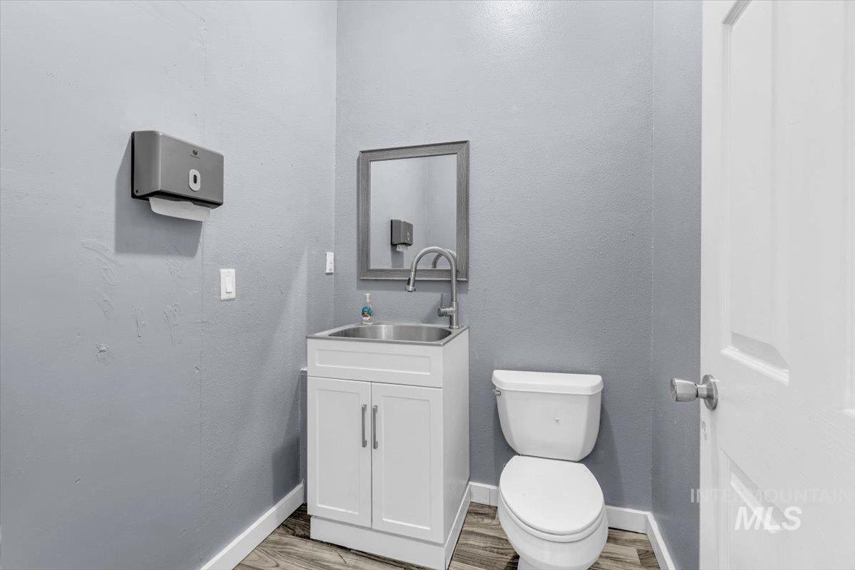 Half bathroom with vanity, a textured wall, and light wood-style flooring