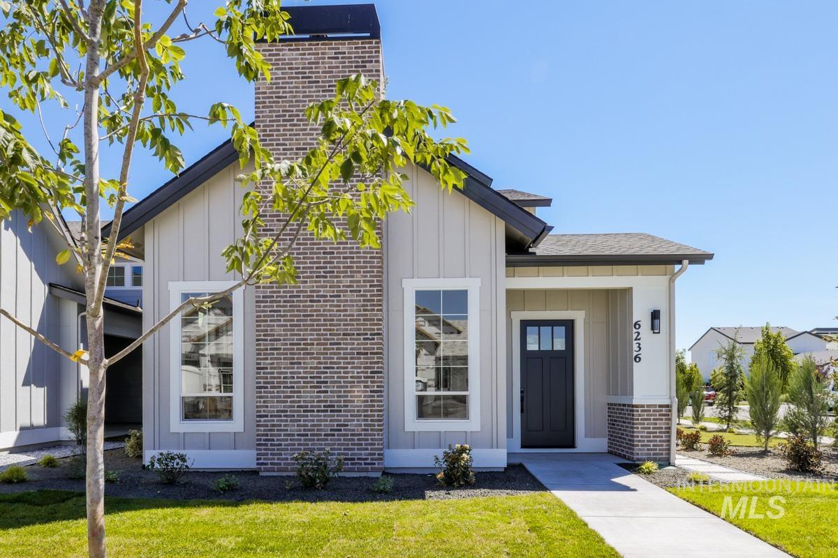 Modern farmhouse style home featuring board and batten siding, a front lawn, brick siding, and a shingled roof