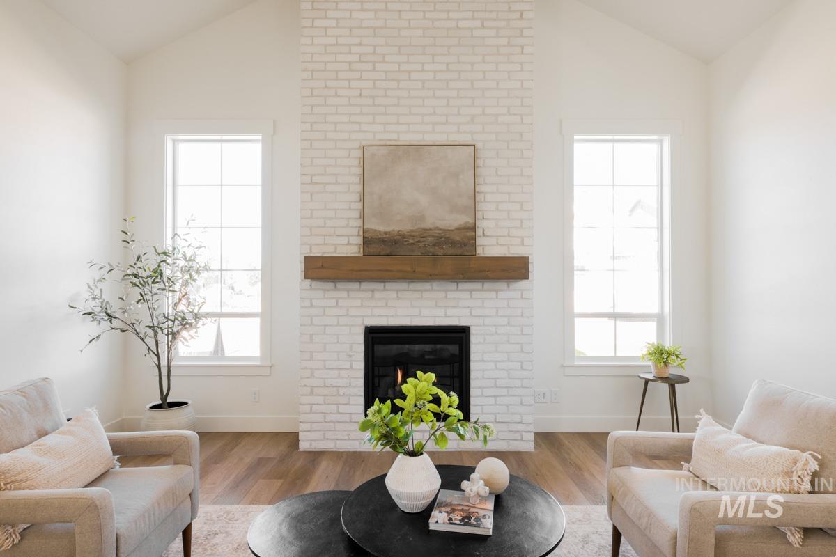 Living room featuring lofted ceiling, a fireplace, wood finished floors, and healthy amount of natural light