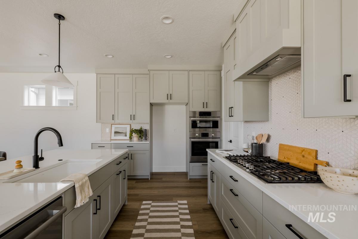 Kitchen featuring hanging light fixtures, stainless steel appliances, recessed lighting, dark wood finished floors, and wall chimney exhaust hood