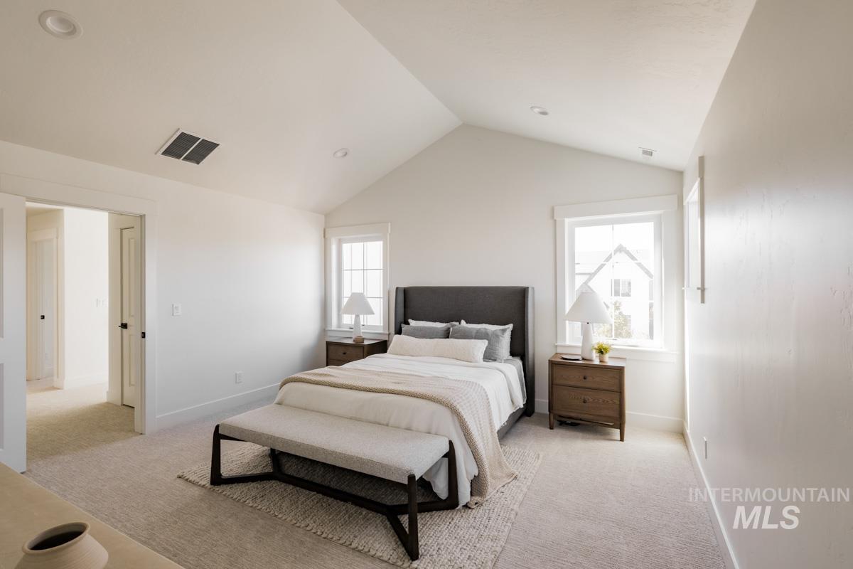 Bedroom featuring light carpet, multiple windows, and lofted ceiling