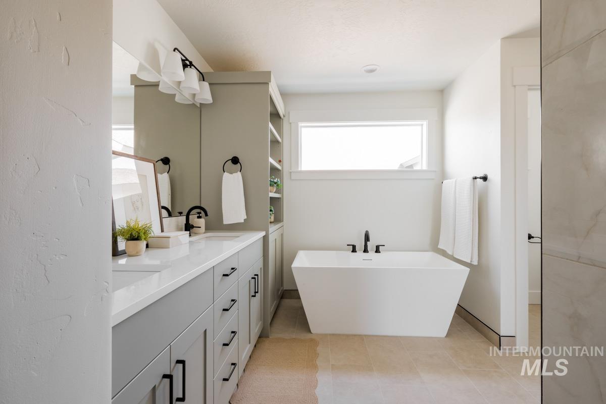 Full bathroom featuring double vanity, a freestanding tub, and light tile patterned floors