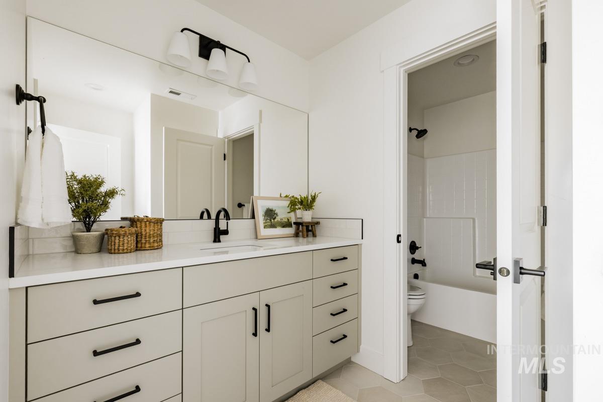 Bathroom featuring vanity, light tile patterned floors, and washtub / shower combination