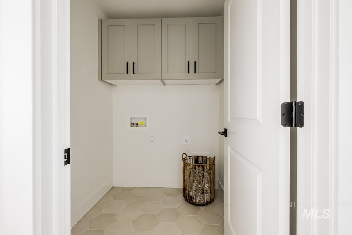 Laundry room featuring hookup for a washing machine, cabinet space, and light tile patterned floors