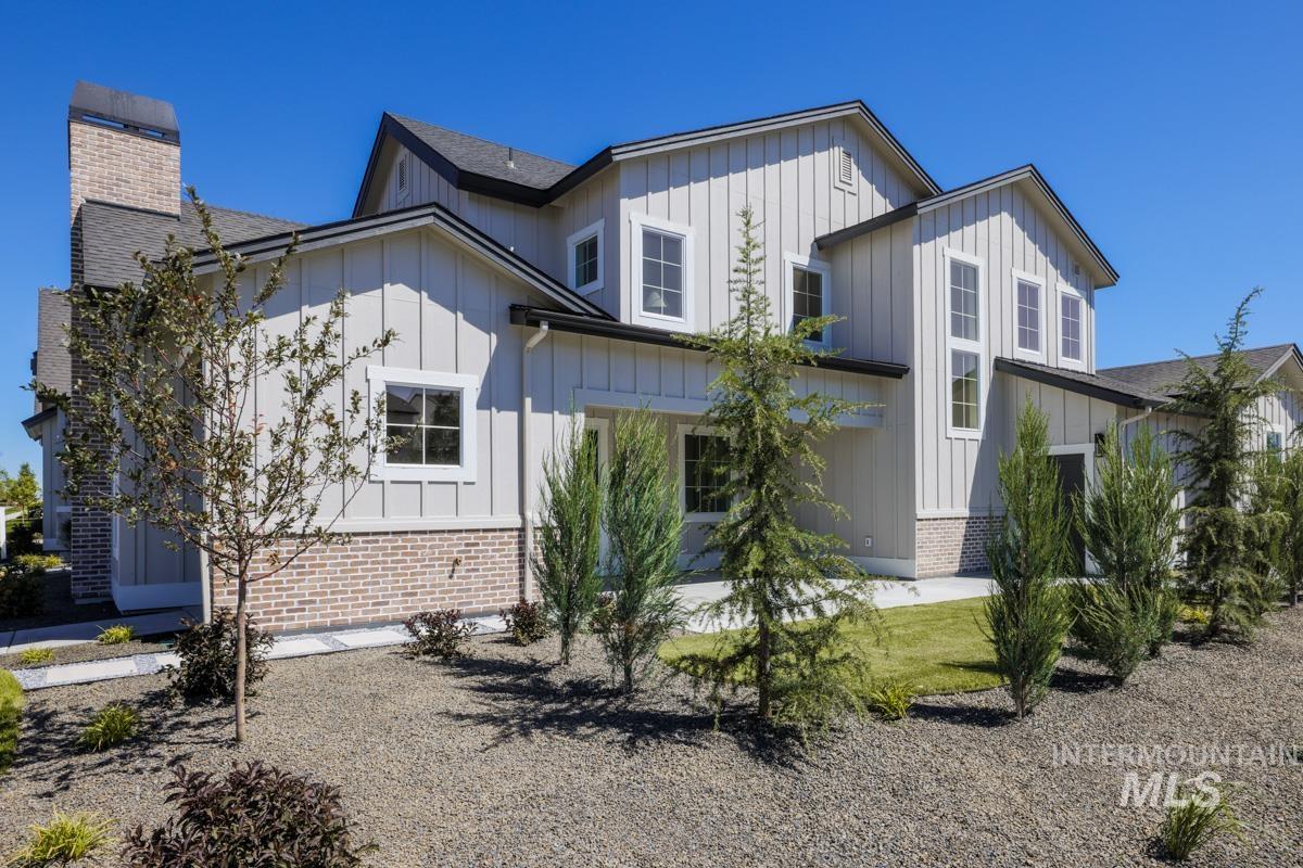 Rear view of property with board and batten siding, brick siding, and a shingled roof