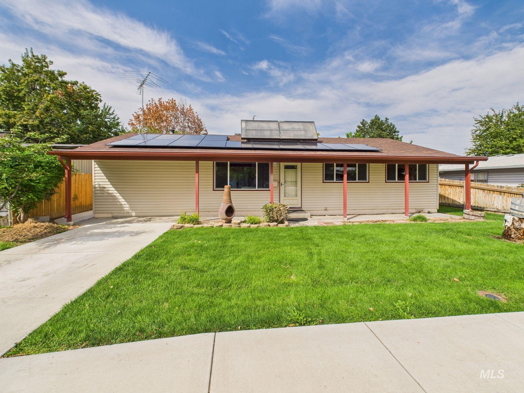 Ranch-style house with solar panels, driveway, and an attached carport