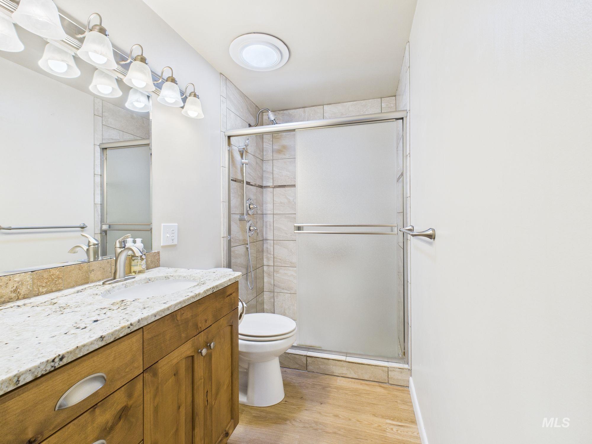 Full bath with vanity, a shower stall, and light wood finished floors
