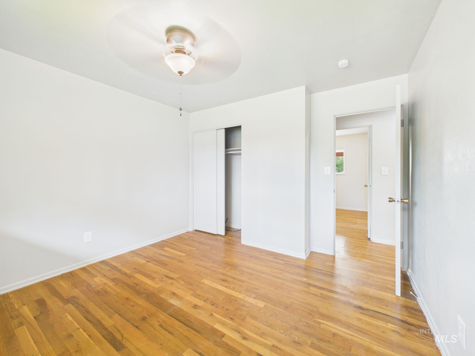 Unfurnished bedroom featuring light wood finished floors, a closet, and ceiling fan