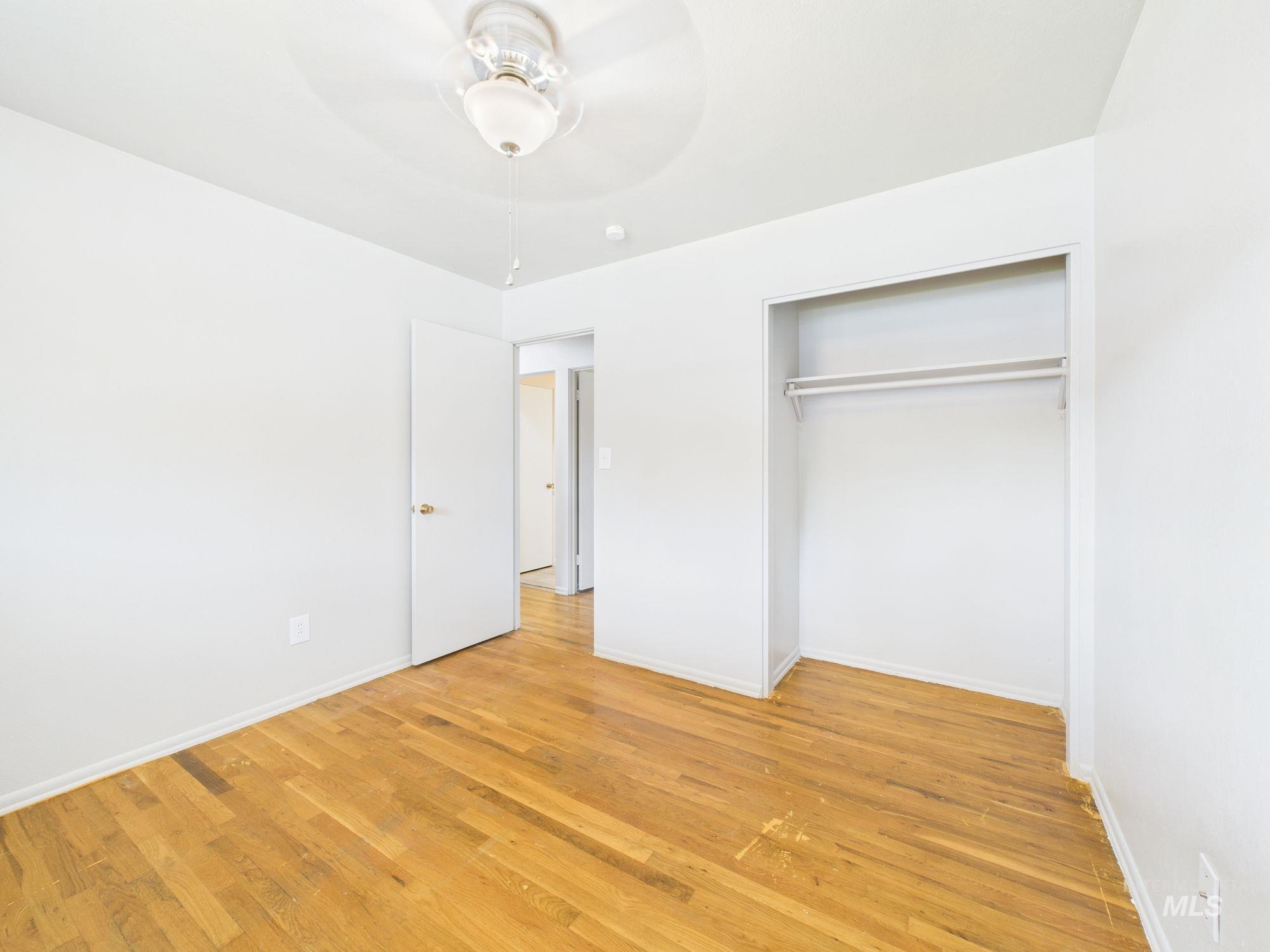 Unfurnished bedroom with light wood-style floors, ceiling fan, and a closet