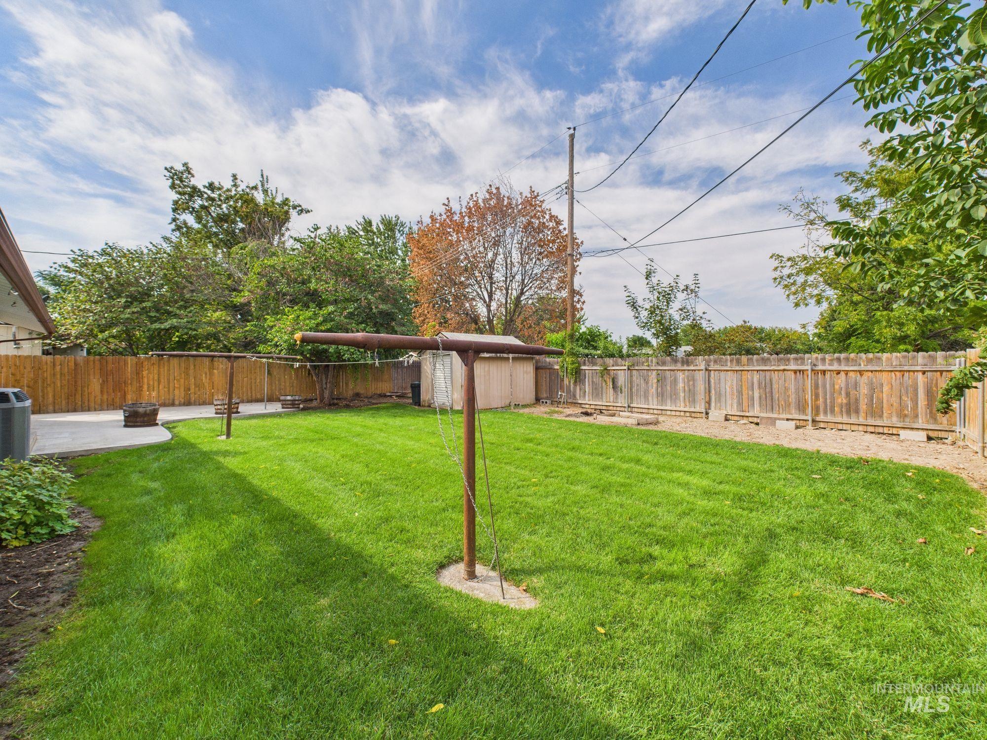 Fenced backyard with a patio area and a storage unit