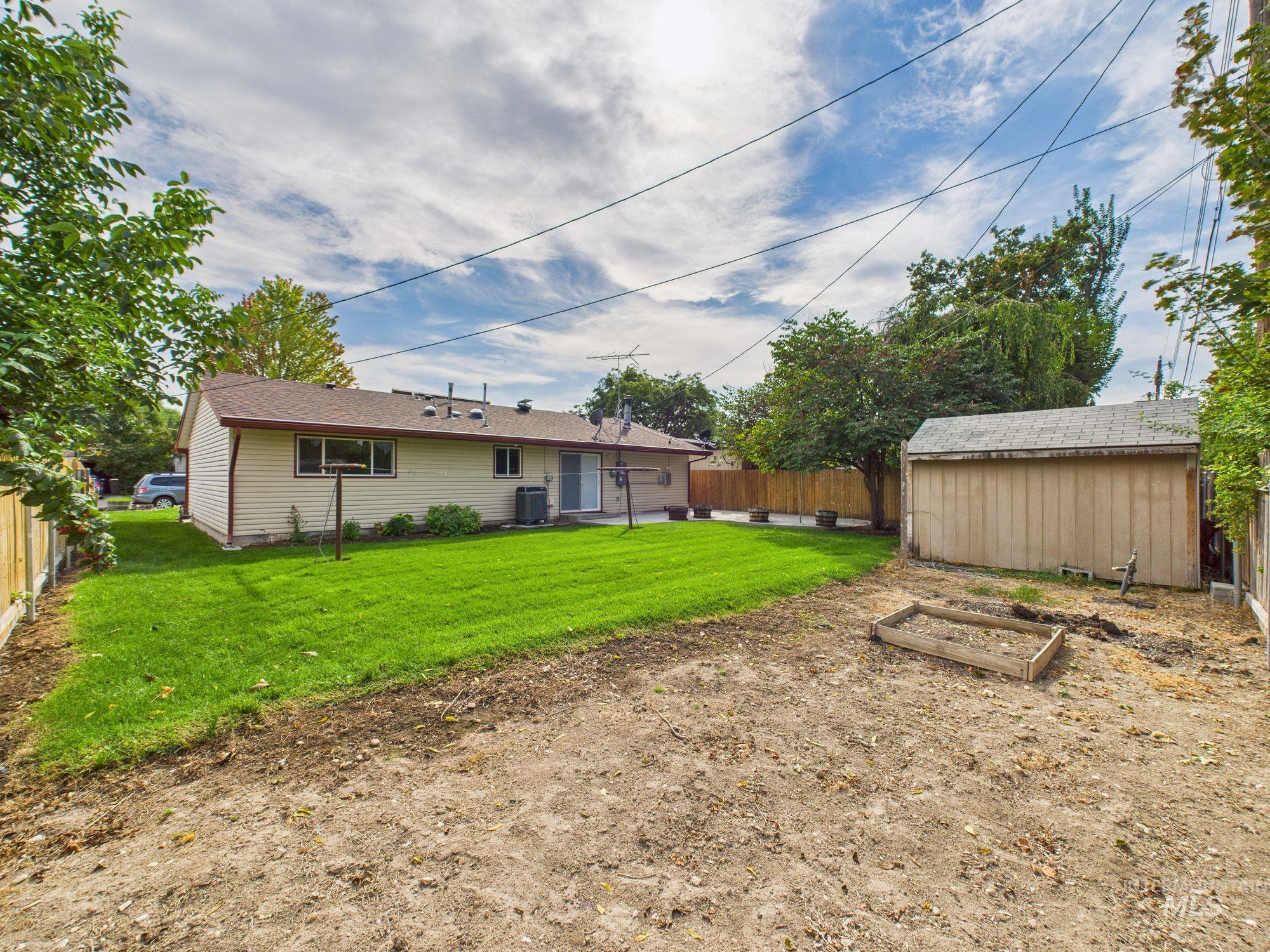 Back of house featuring a garden, a fenced backyard, a patio, and an outbuilding