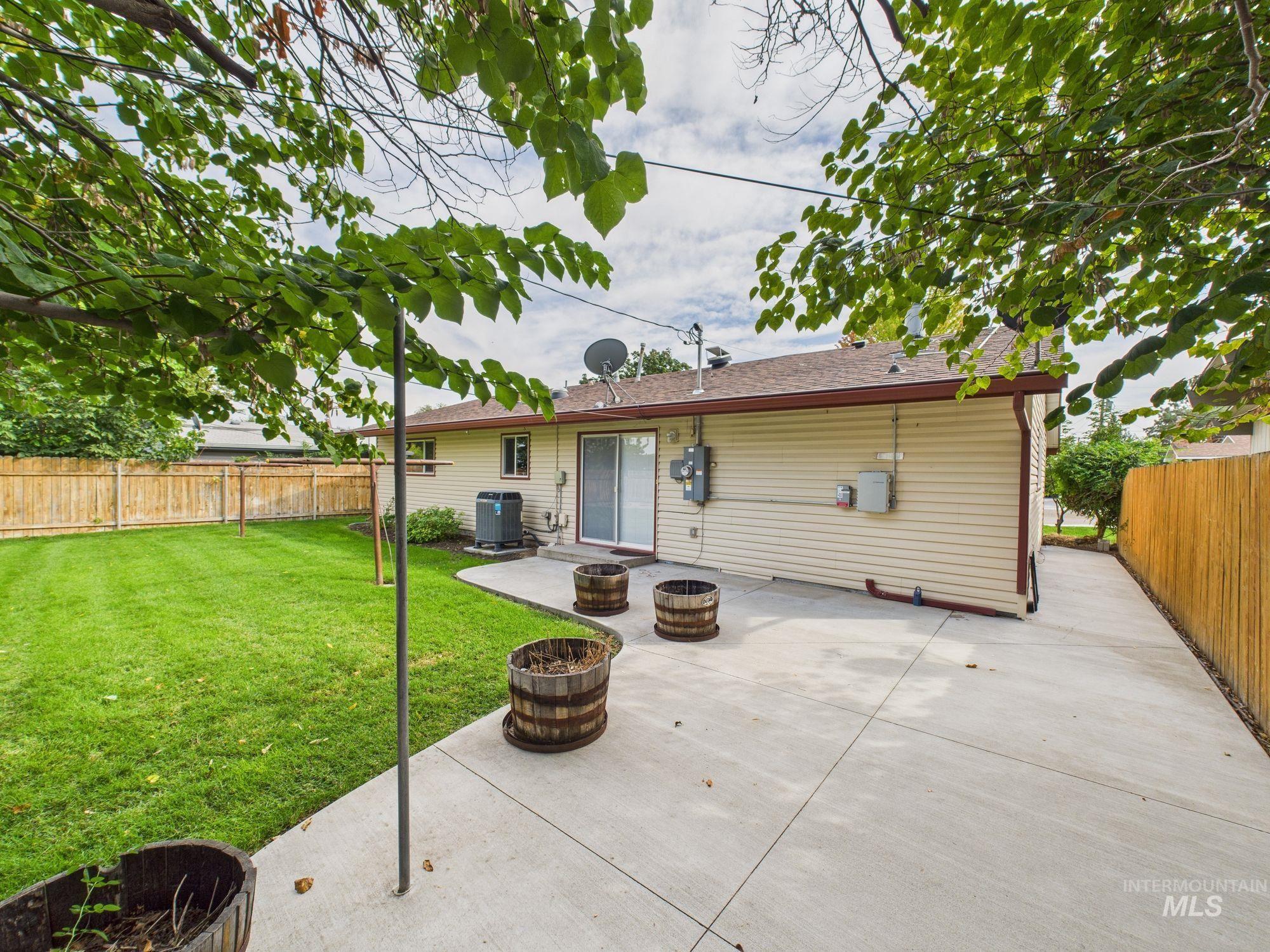 Rear view of house featuring a fenced backyard, an outdoor fire pit, a patio area, and a shingled roof
