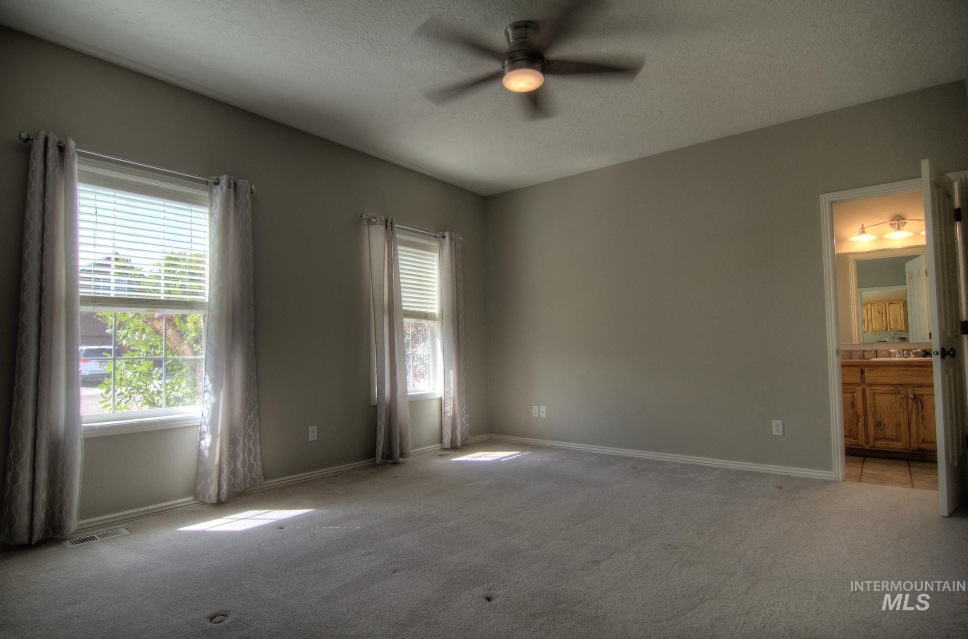 Unfurnished bedroom featuring carpet floors, connected bathroom, ceiling fan, and a textured ceiling