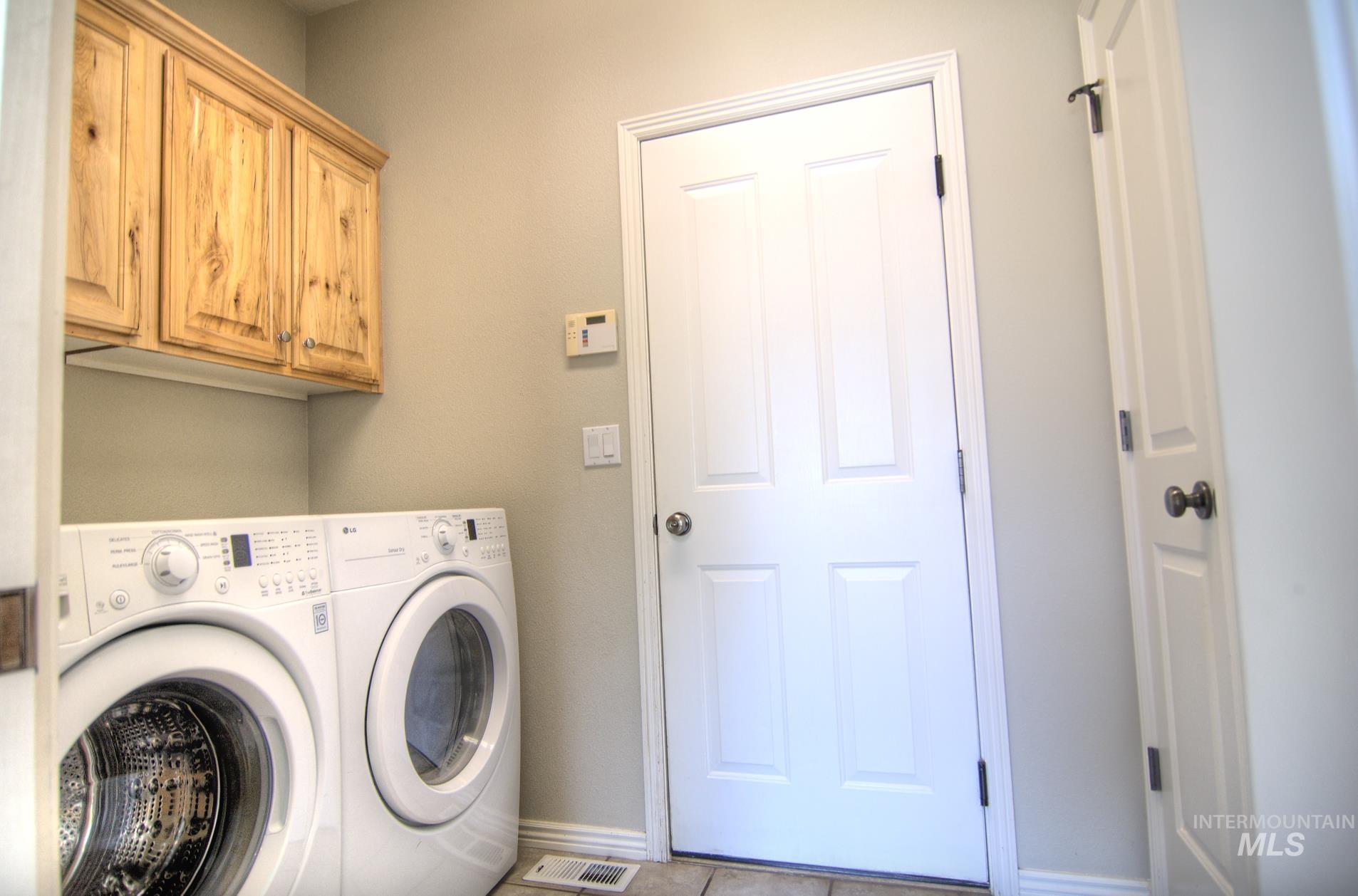 Laundry area with separate washer and dryer, cabinet space, and tile patterned flooring