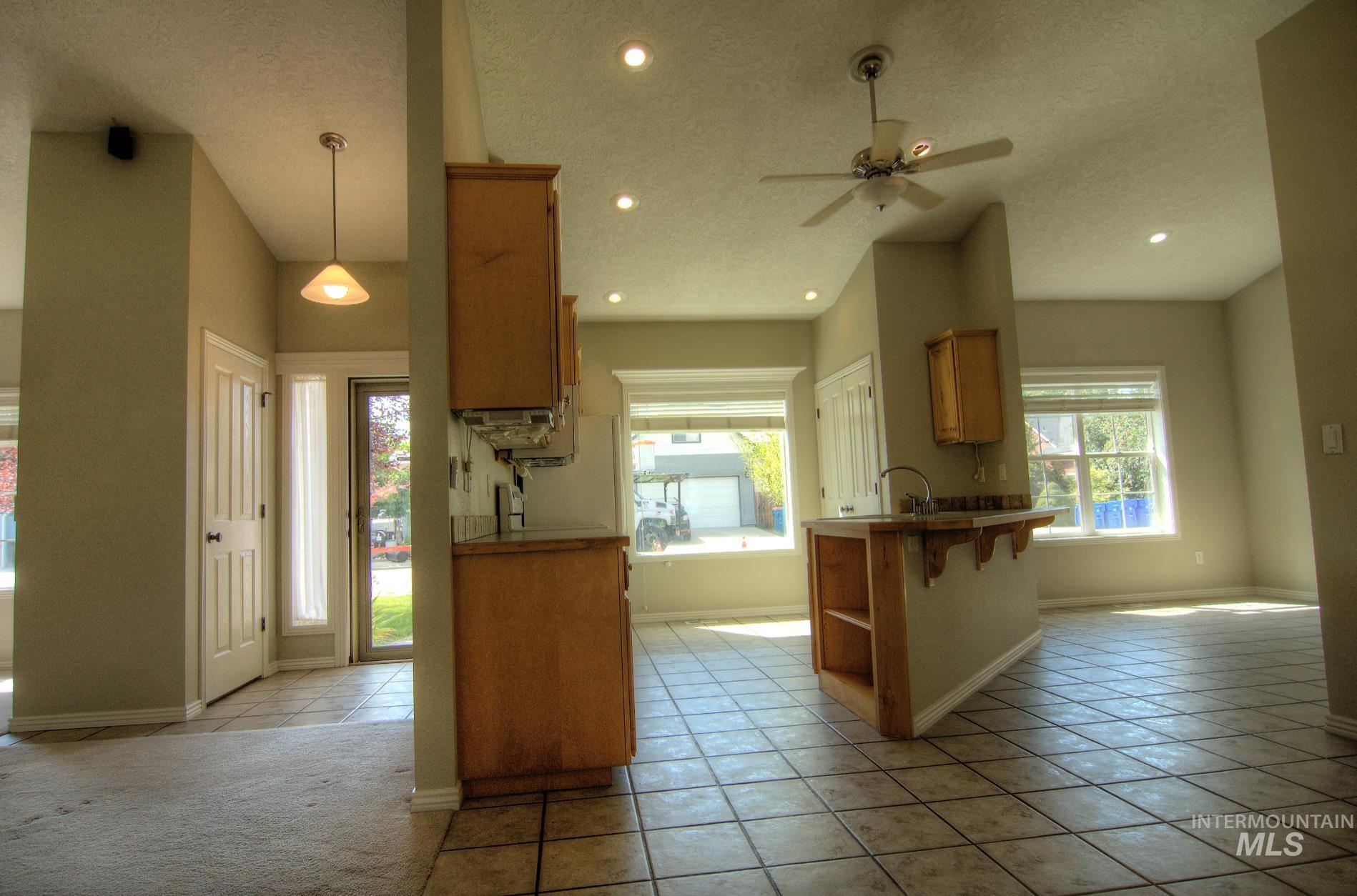 Kitchen featuring a breakfast bar area, light tile patterned flooring, brown cabinetry, a textured ceiling, and a peninsula